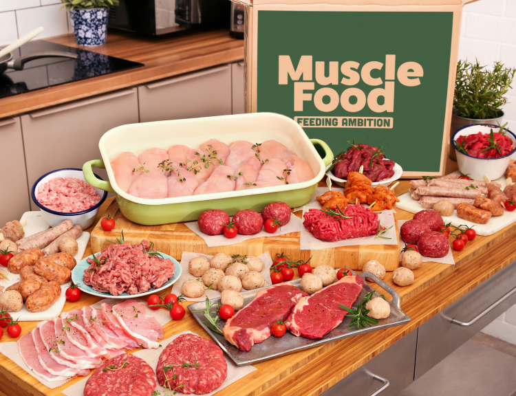 A large selection of raw meats arranged around a delivery box