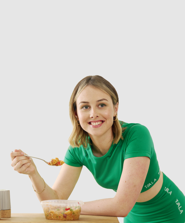 Athletic woman in sports wear eating a MuscleFood ready meal