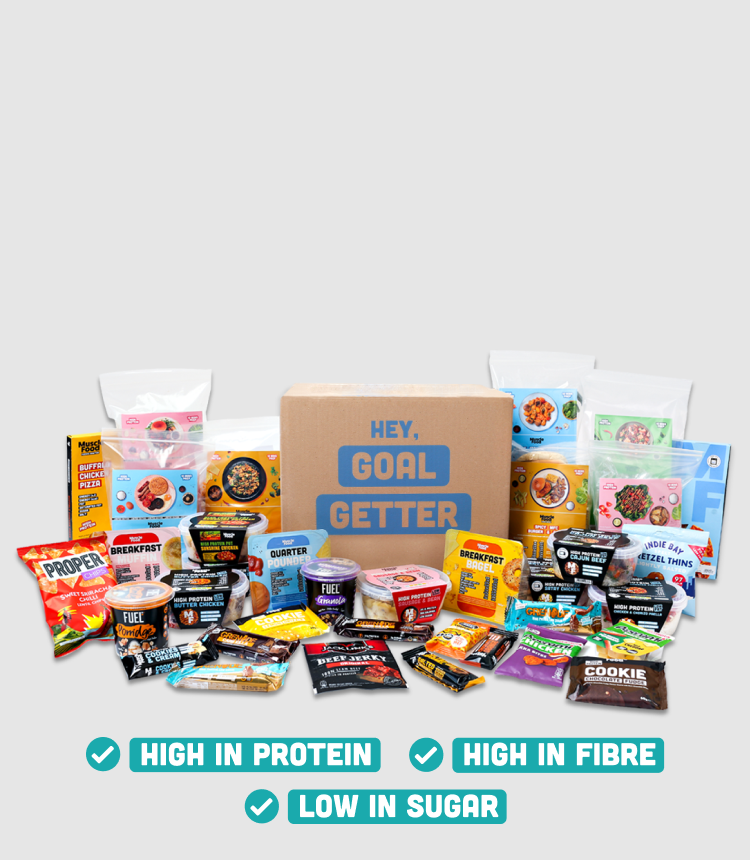 A large cariety of ready meals, recipe kits and snacks arranged around a Goal Getters delivery box