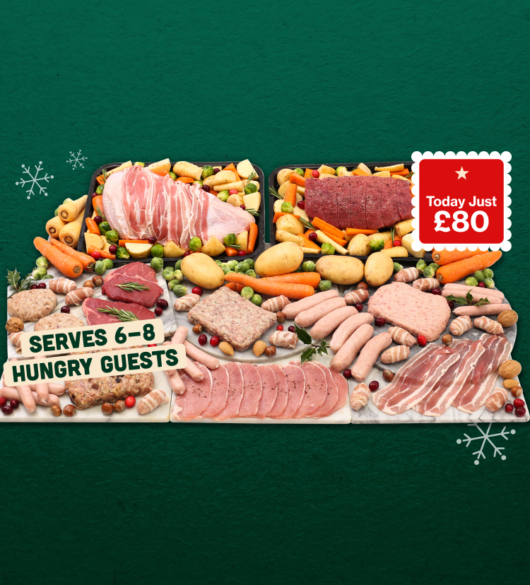 A Christmas turkey breast wrapped in bacon and beef roasting joint arranged with various raw meats and vegetables