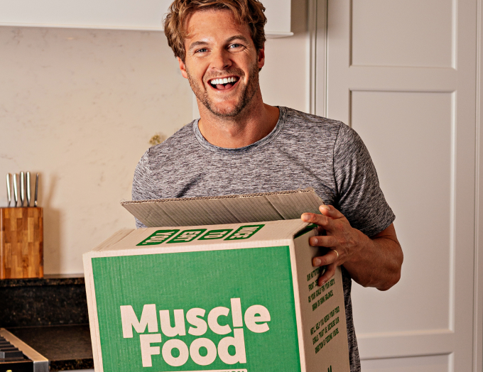 A fit young man unpacking a MuscleFood delivery in his kitchen